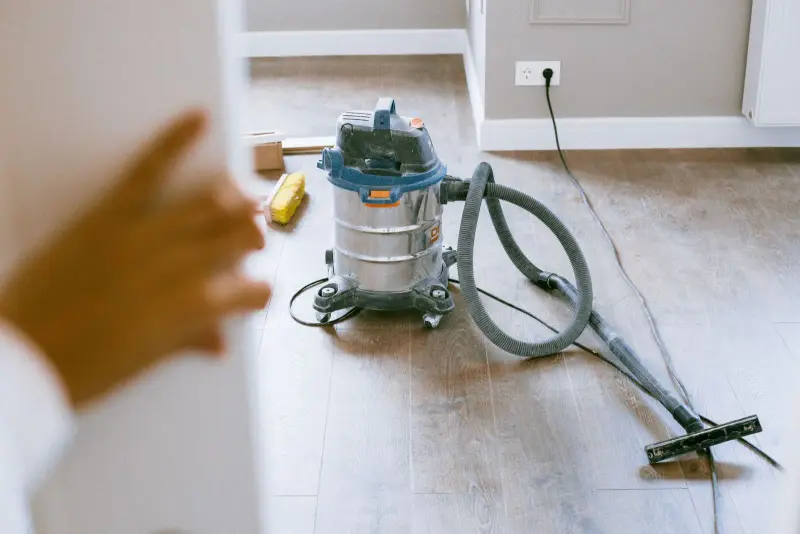 A shop vacuum on a newly laid wood floor in a renovated room