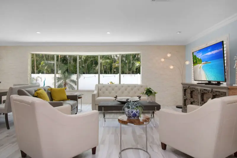 A staged living room with neutral furniture and polished floors